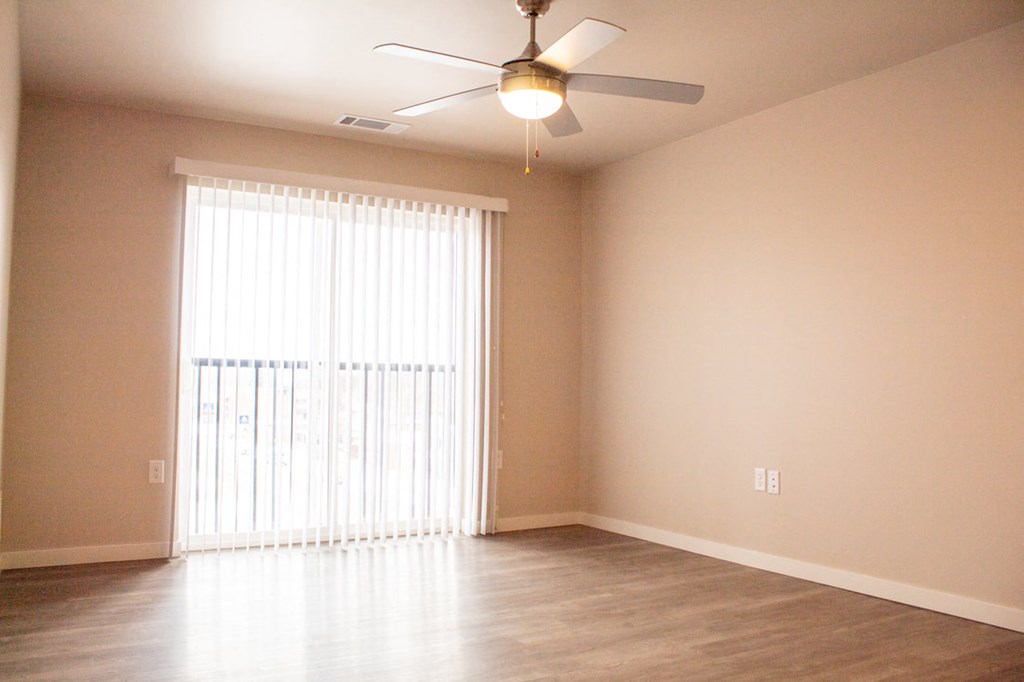 an empty living room with a window and a ceiling fan