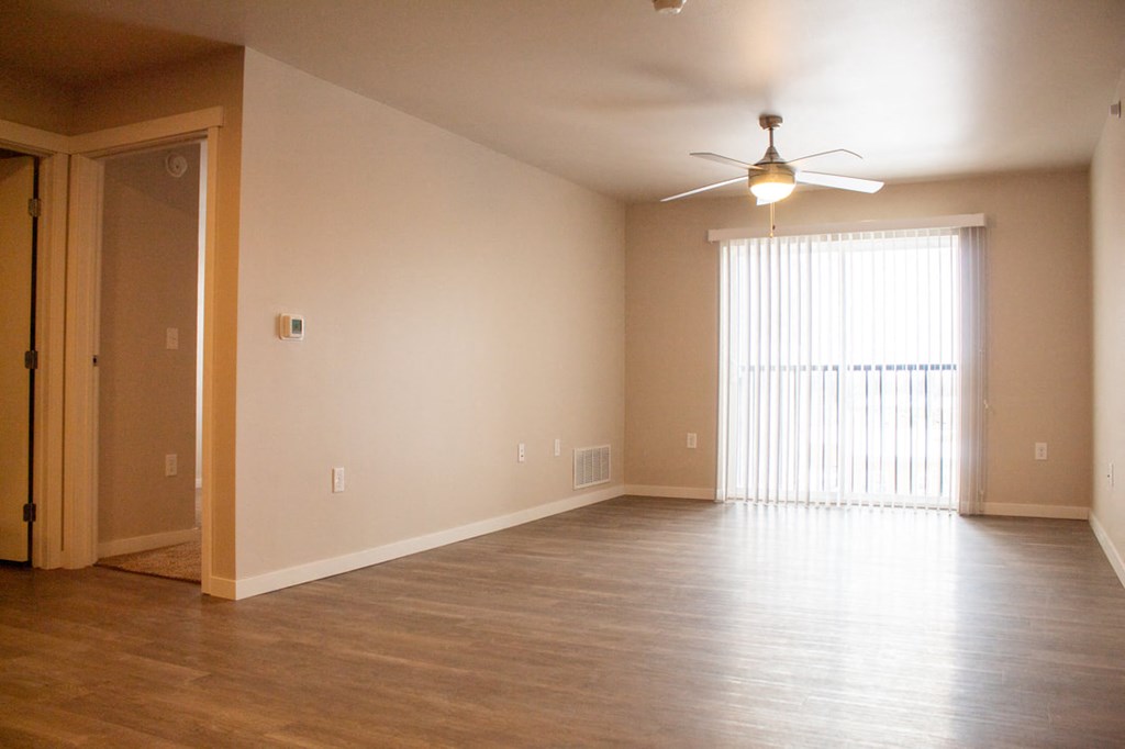 an empty living room with a ceiling fan and a window