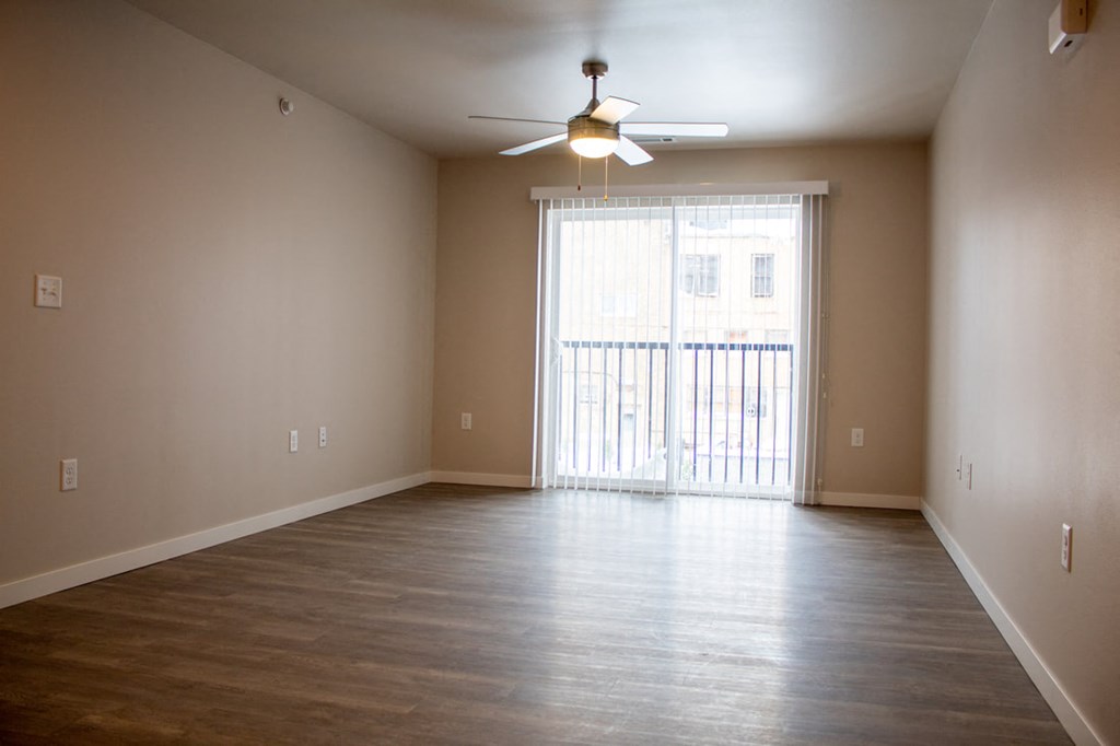 an empty living room with wood floors and a ceiling fan