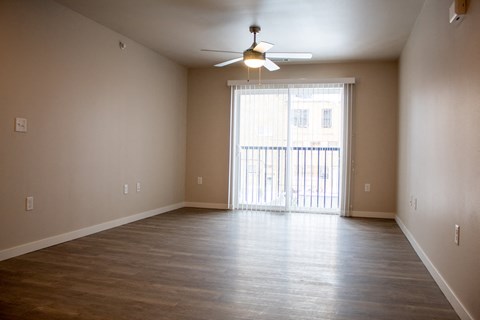 an empty living room with wood floors and a ceiling fan
