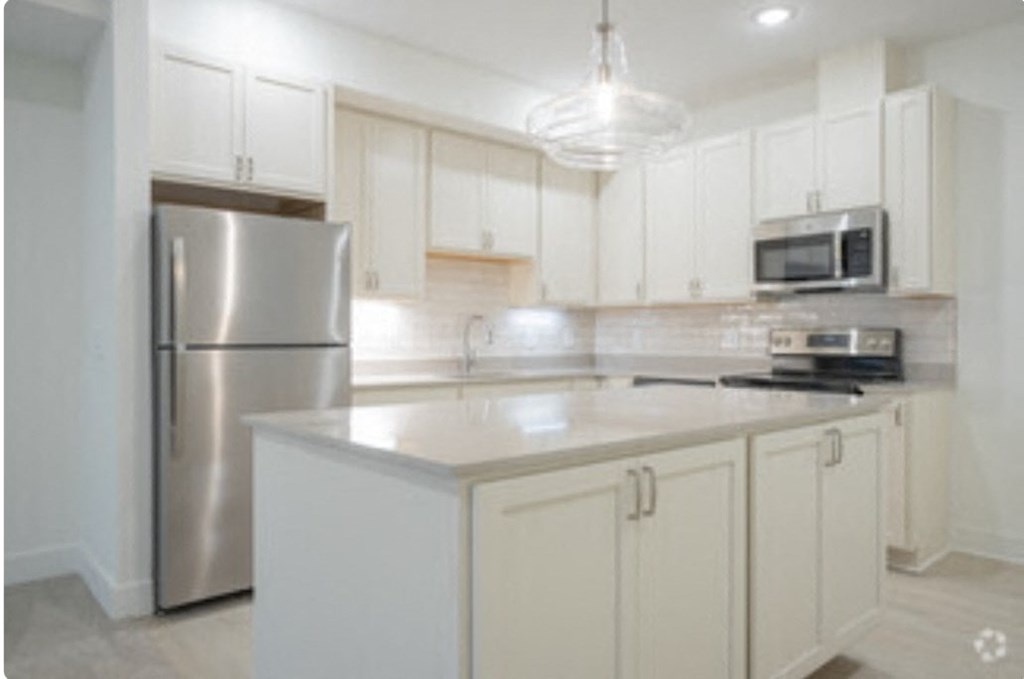 a kitchen with white cabinets and a stainless steel refrigerator