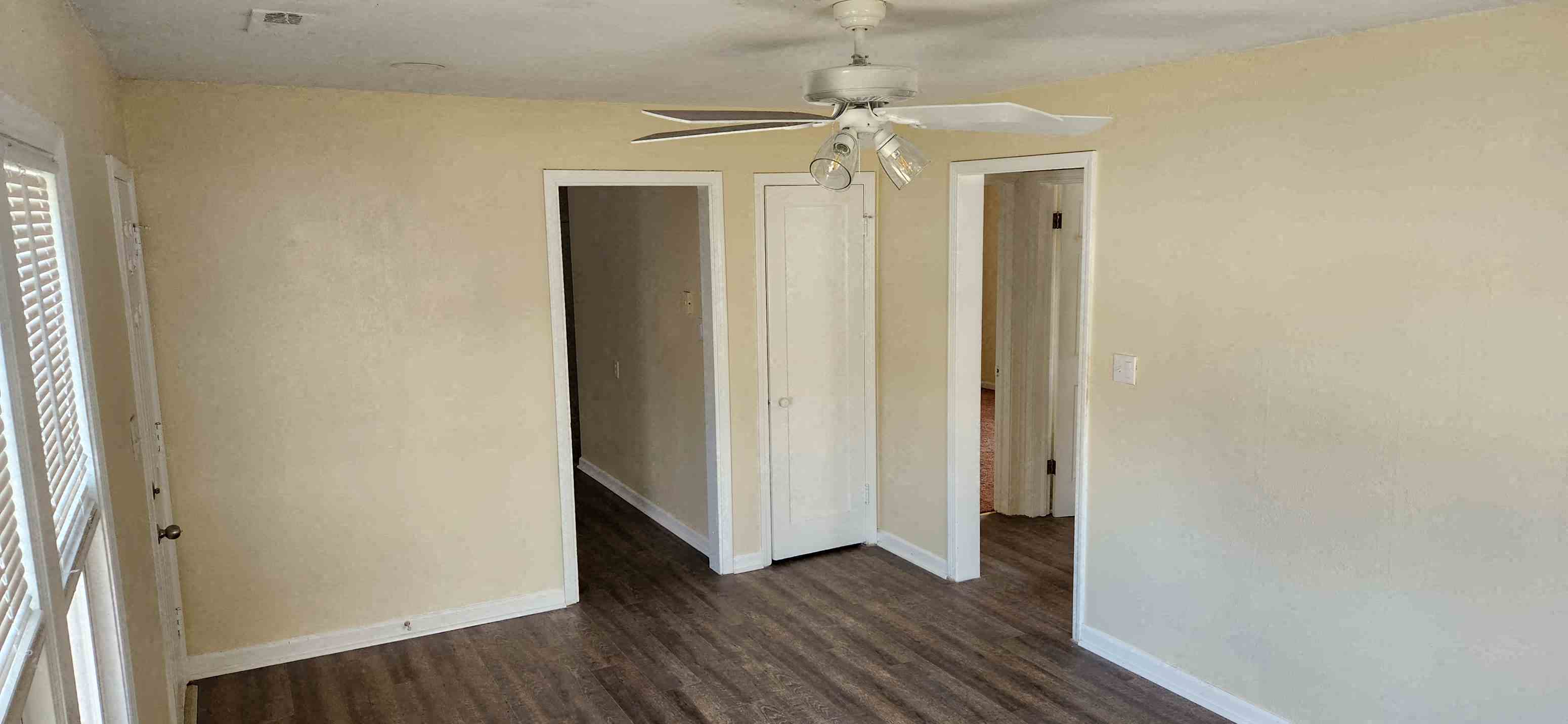 A room with a ceiling fan and wooden floors.