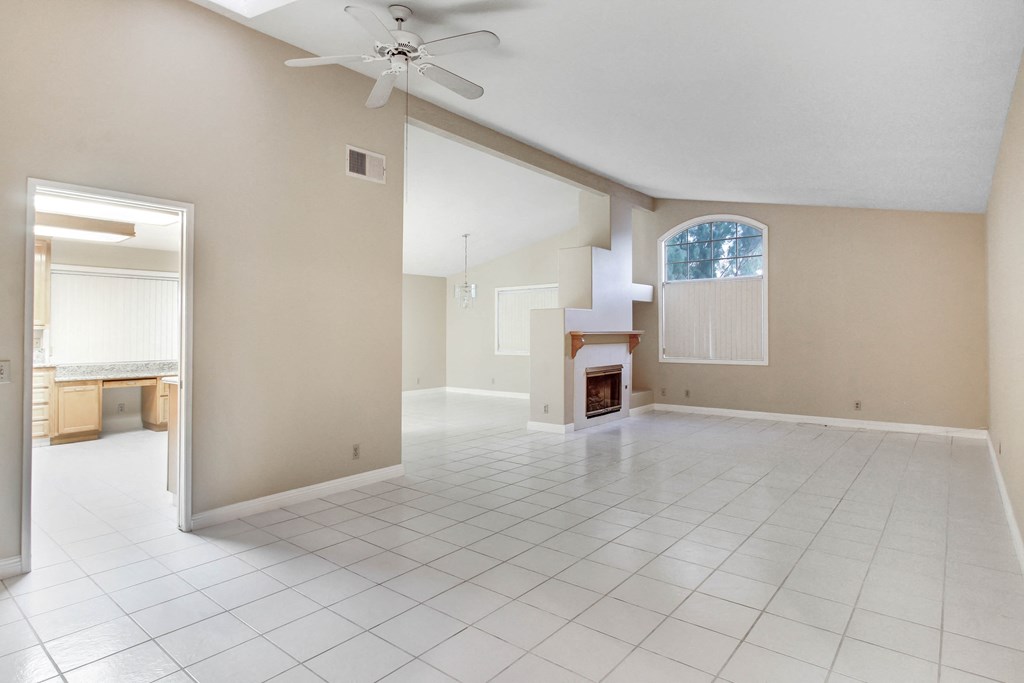 A spacious room with a fireplace and a ceiling fan.