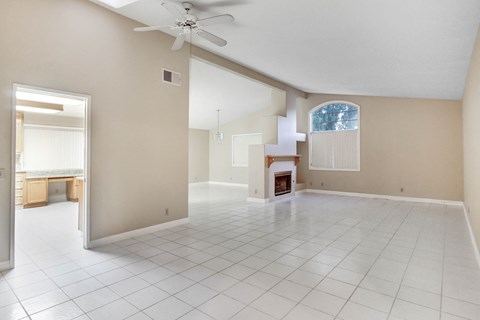 A spacious room with a fireplace and a ceiling fan.
