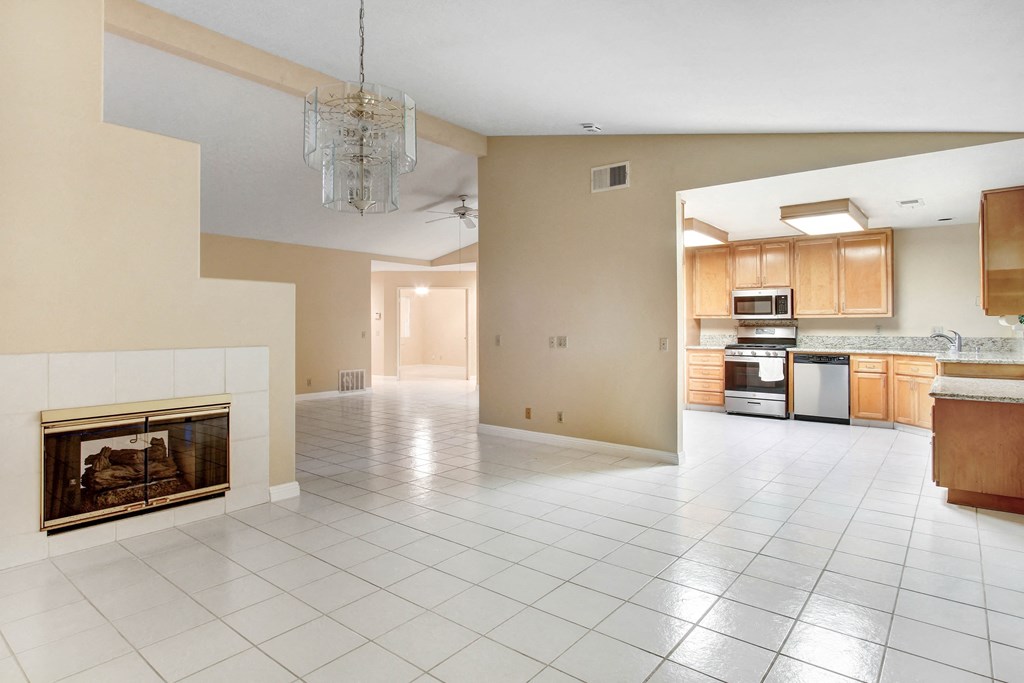 A large open living space with a fireplace and a kitchen area.