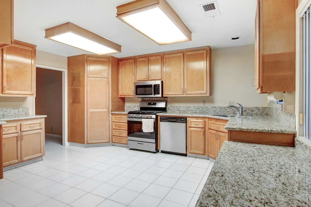 A kitchen with wooden cabinets and a white tile floor.
