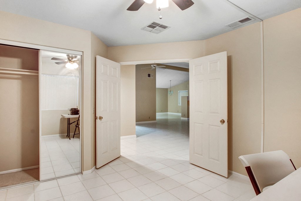 A room with a ceiling fan and a table with a chair.