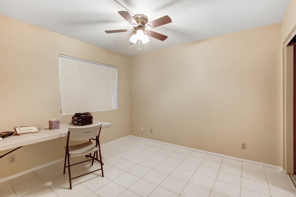 A room with a ceiling fan and a whiteboard on the wall.