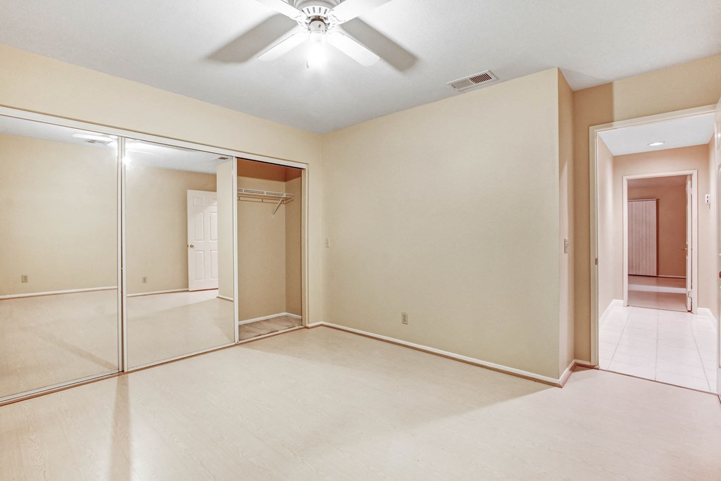 A room with a ceiling fan and sliding glass doors.