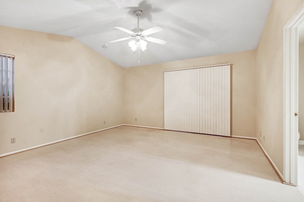 A room with a ceiling fan and a window with blinds.