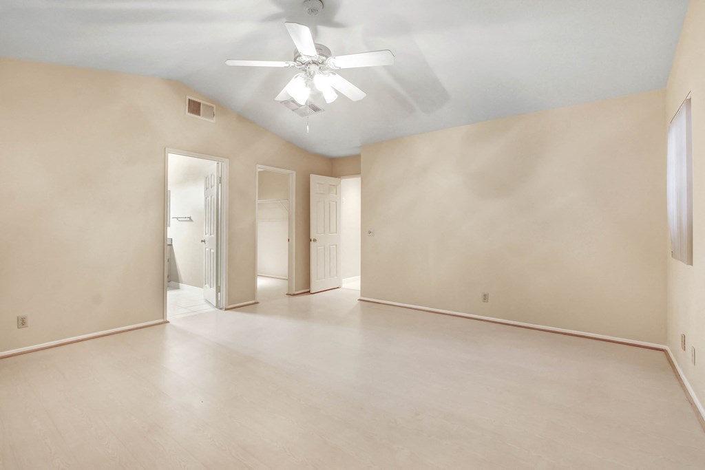 A room with a ceiling fan and light, and a doorway leading to another room.