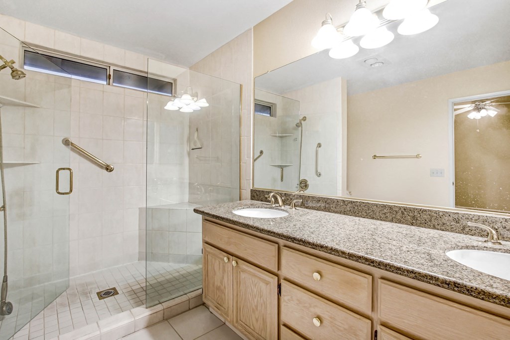 A bathroom with a walk-in shower, double sinks, and a large mirror.