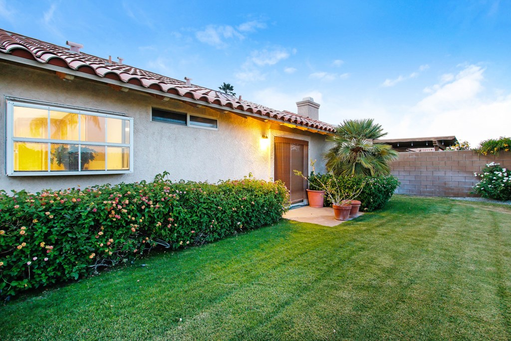 A house with a red tile roof and a green lawn.