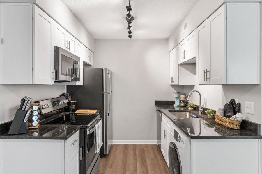 a kitchen with white cabinets and black counter tops