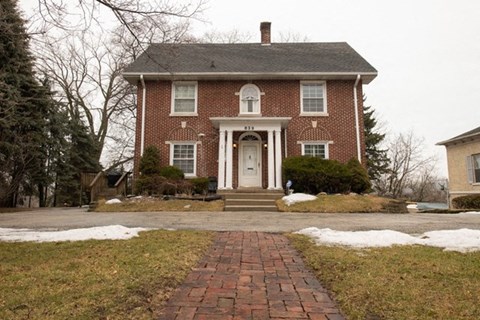A red brick house with a white door and a brick pathway leading to it.