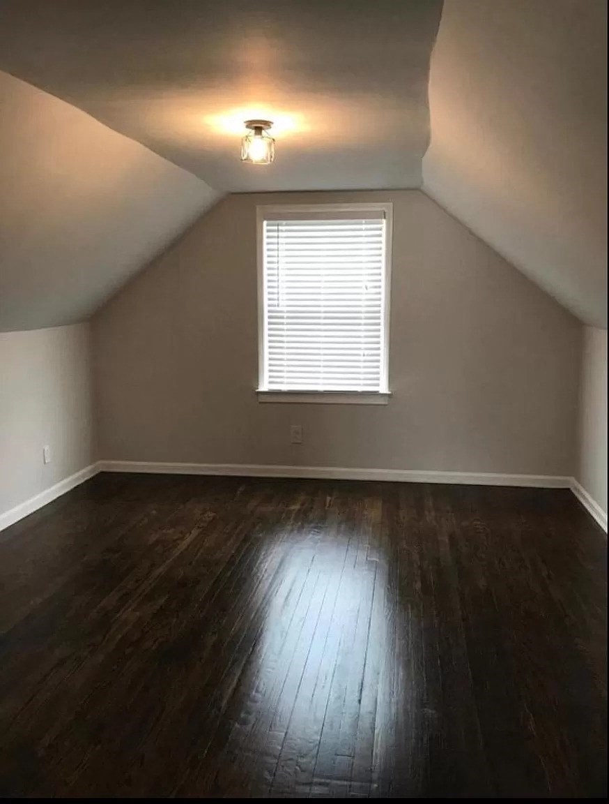 an empty room with wooden floors and a window