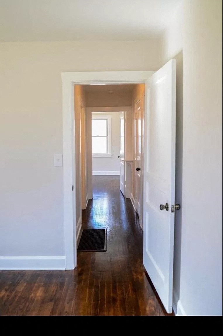 a hallway with a wood floor and white walls