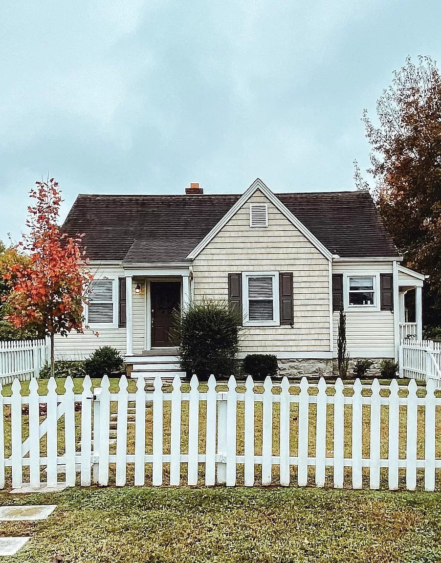 a small house with a white fence in front of it