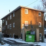 a brown building with a green recycling bin in front of it