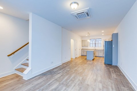 A spacious room with a staircase and a kitchenette.