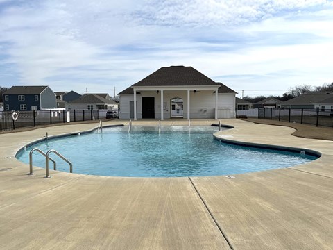 A pool with a diving board and a small building in the background.