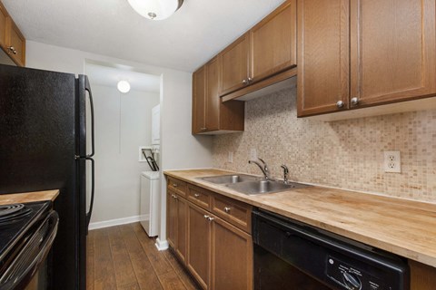 A kitchen with a black refrigerator and wooden cabinets.