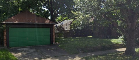 a green garage door in front of a yard with trees