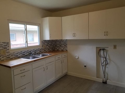 a kitchen with white cabinets and a sink and a window
