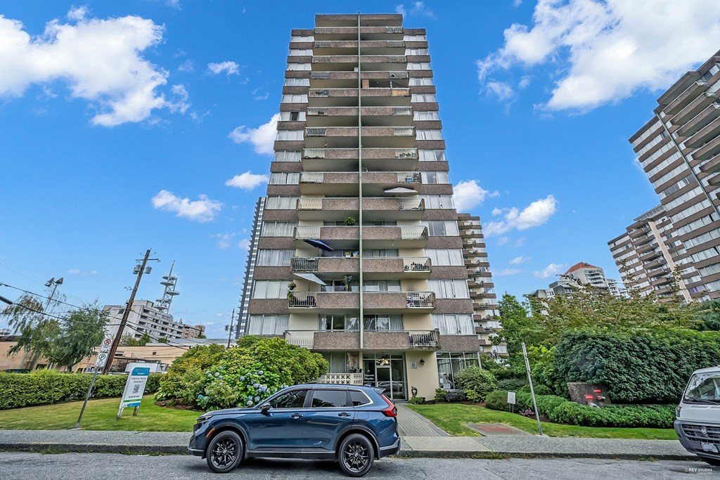 A tall residential building with a blue sky and clouds in the background.