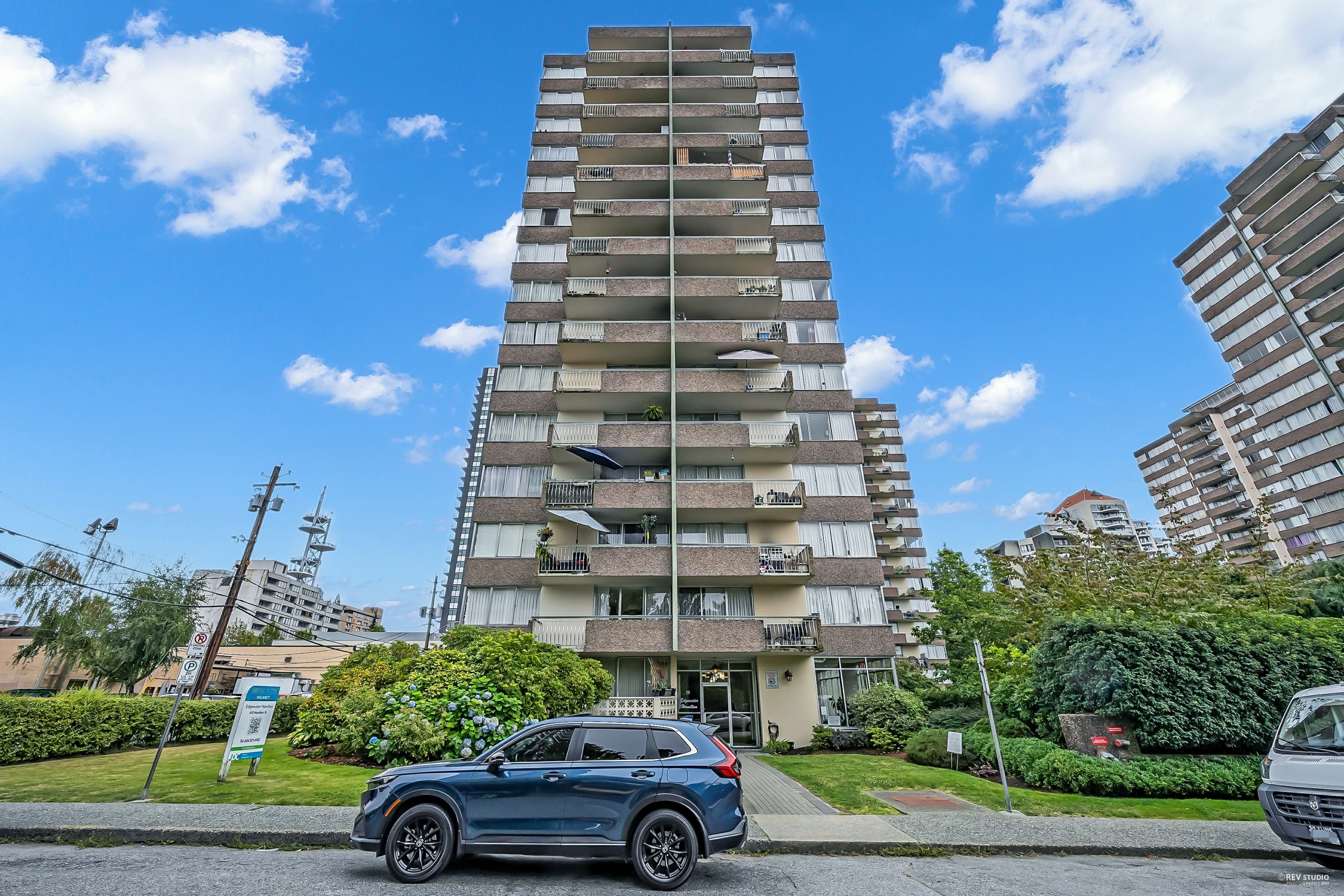 A tall residential building with a blue sky and clouds in the background.