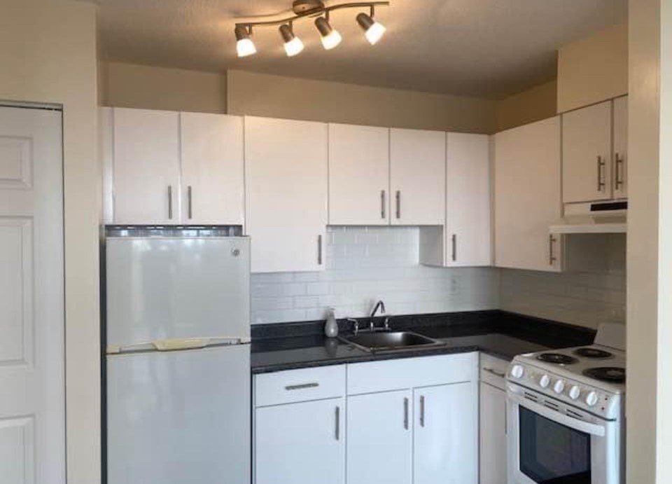 A kitchen with white appliances and cabinets.