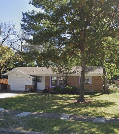 a small brick house with a tree in front of it