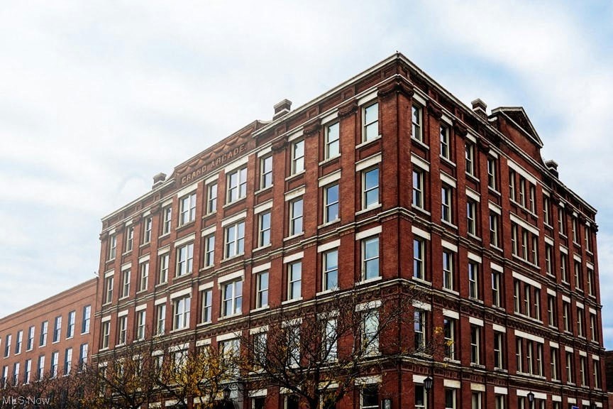 a tall red brick building with a cloudy sky