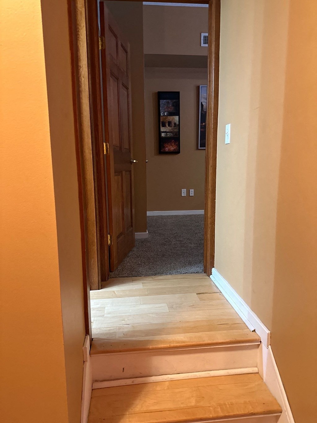 a wooden staircase leading up to a room with a door and carpet