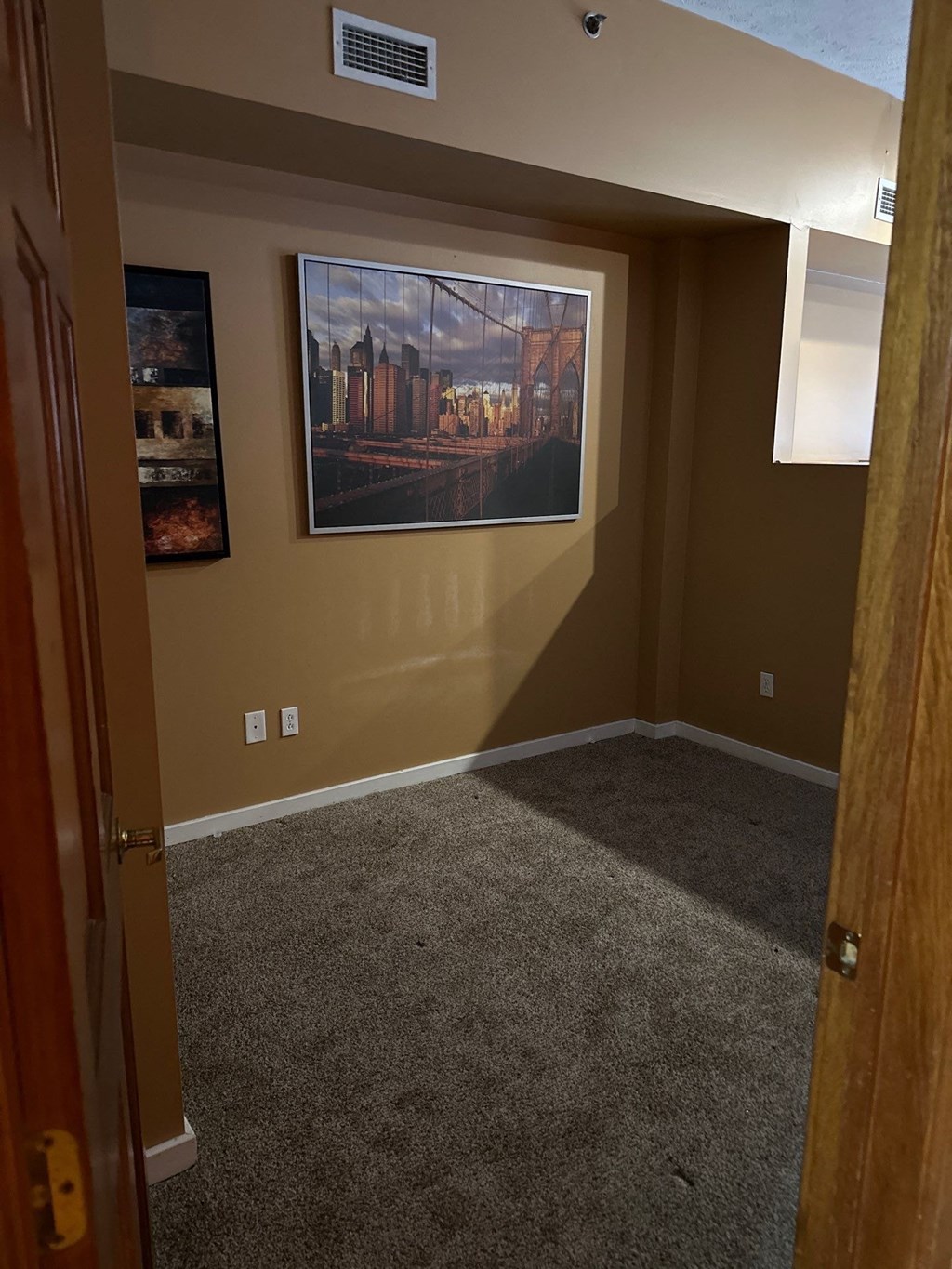 a carpeted room with a painting on the wall