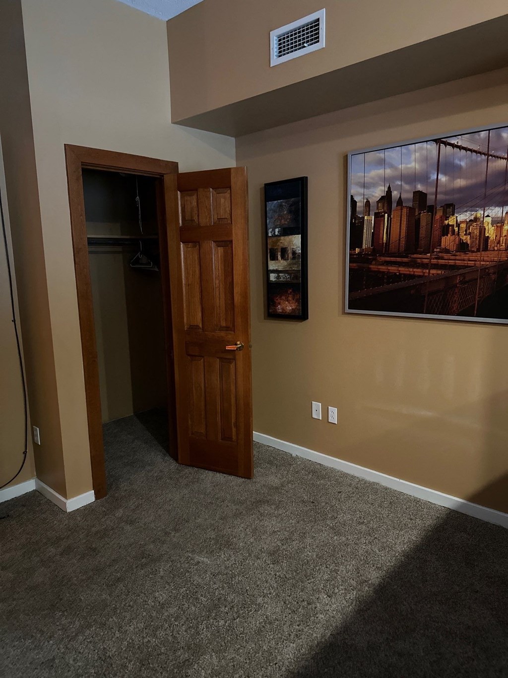a carpeted room with a door and paintings on the wall