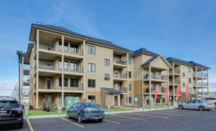 an apartment building with cars parked in a parking lot