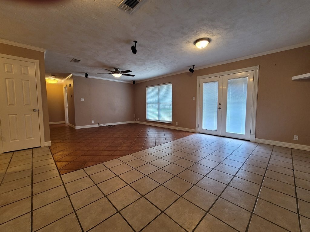 an empty living room with a tile floor and a ceiling fan