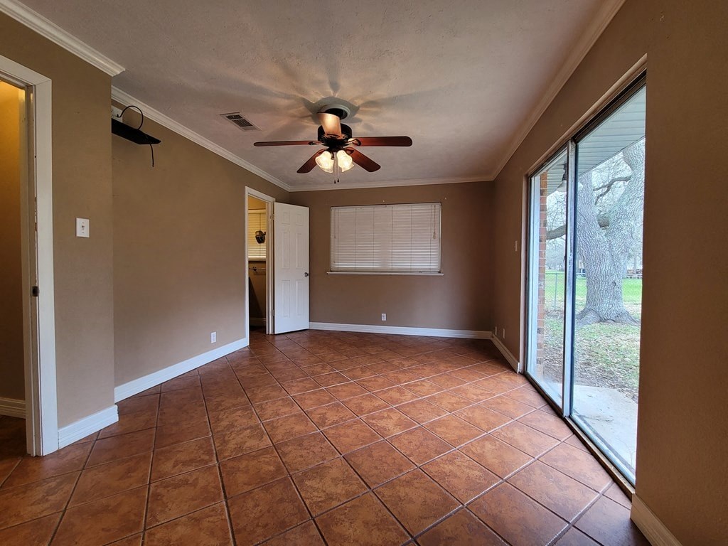 a empty living room with a ceiling fan and a sliding glass door