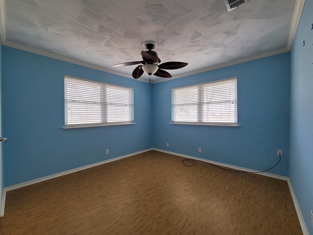 a blue room with a ceiling fan and two windows
