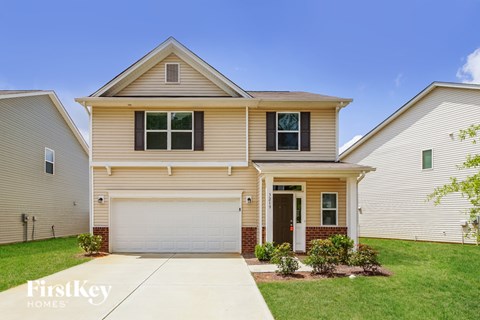 A house with a garage and a driveway in front of it.