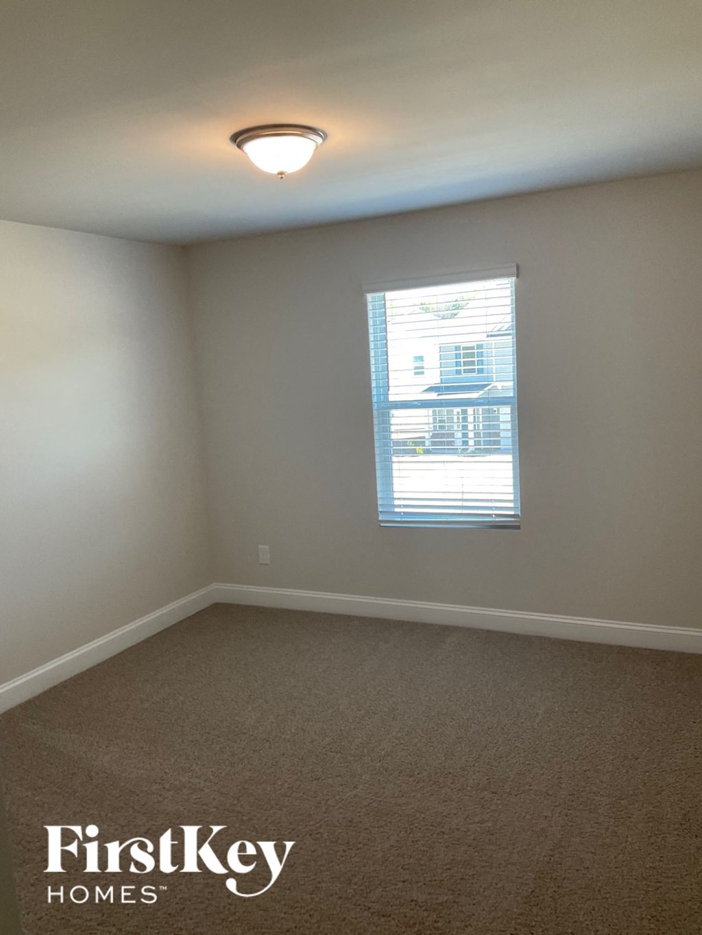 an empty room with a window and a light on the ceiling