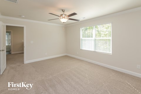 A spacious room with a ceiling fan and carpeted floor.