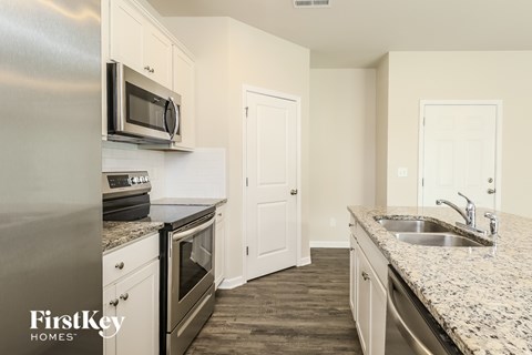 A kitchen with a stainless steel refrigerator, microwave, oven, and sink.