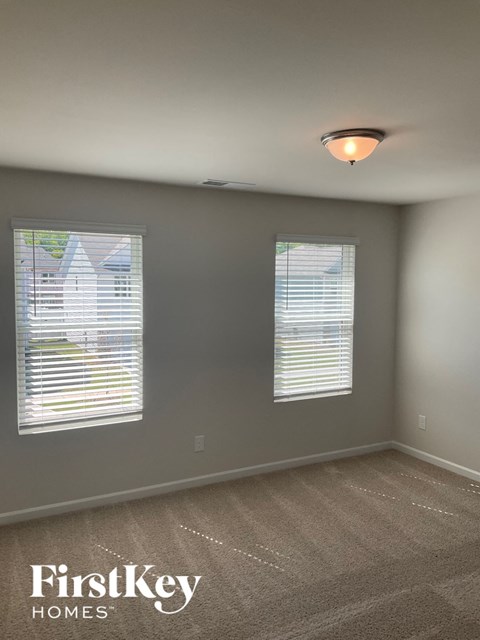 a bedroom with two windows and a carpeted floor