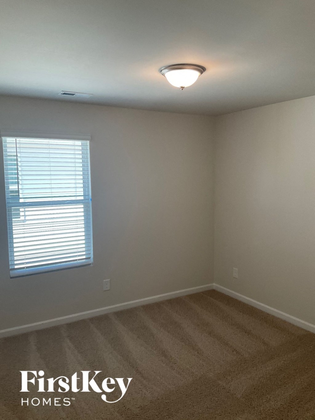 an empty room with a window and a light on the ceiling