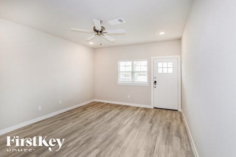 a bedroom with white walls and a white door and a ceiling fan