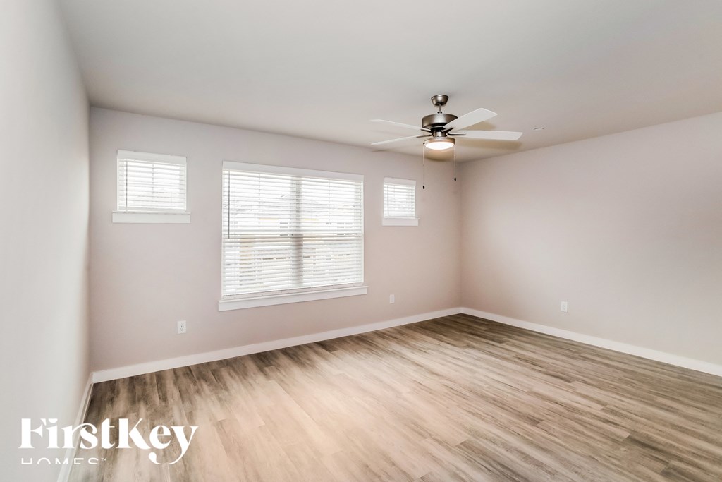 a bedroom with wood floors and a ceiling fan