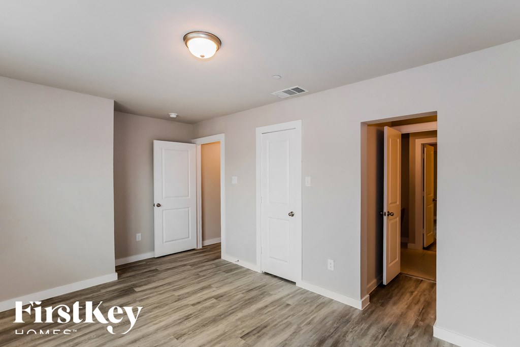 a bedroom with white walls and wood flooring and two doors