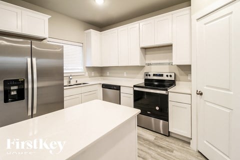 a white kitchen with stainless steel appliances and white counters